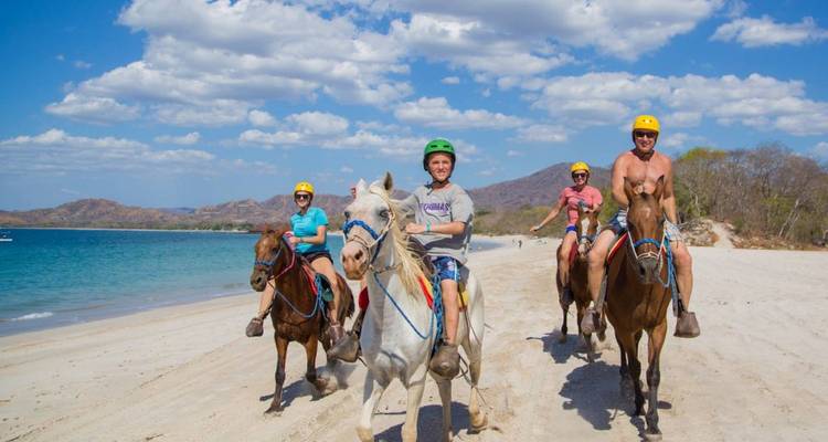 Groupe de personnes faisant de l'équitation sur une plage.