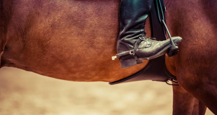 Gros plan d'une botte dans un étrier de cheval.