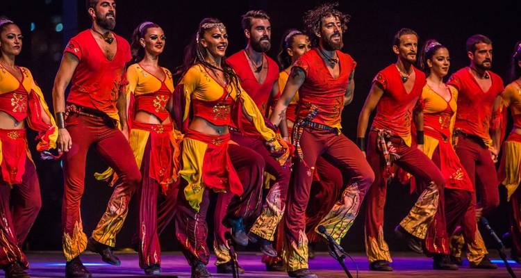 Ensemble de danseurs en costumes rouges se produisant sur scène.