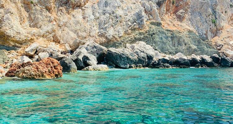 Agua turquesa cristalina con costa rocosa.