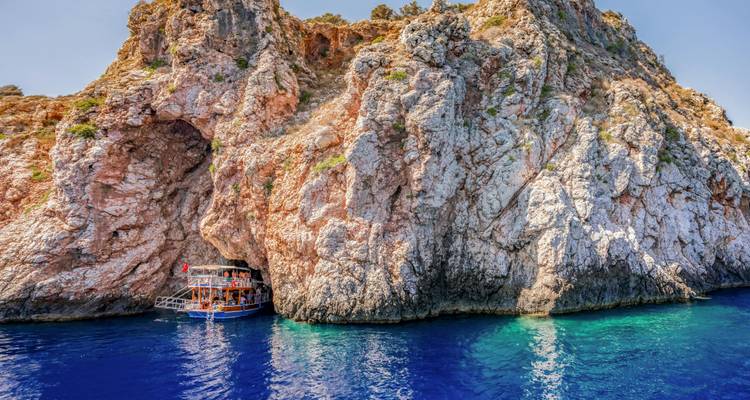 Un barco cerca de un acantilado rocoso con agua azul cristalina.