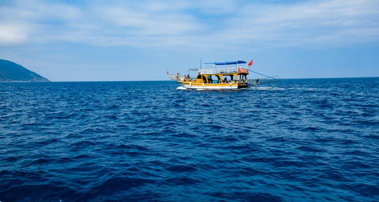 Un barco en mar abierto con colinas distantes.
