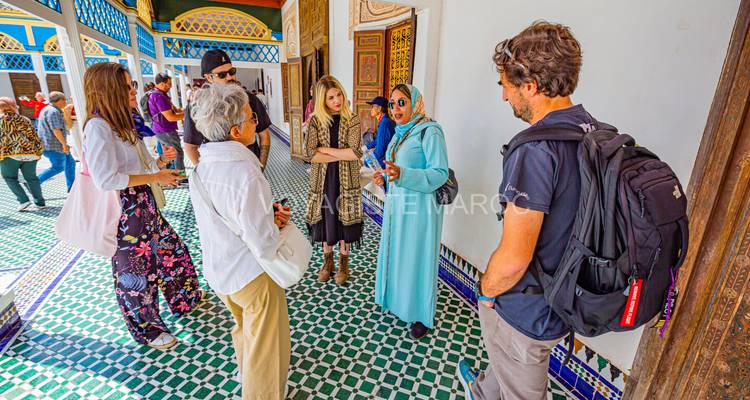 Grupo de personas en un patio con azulejos de mosaico, una persona vistiendo atuendo tradicional.