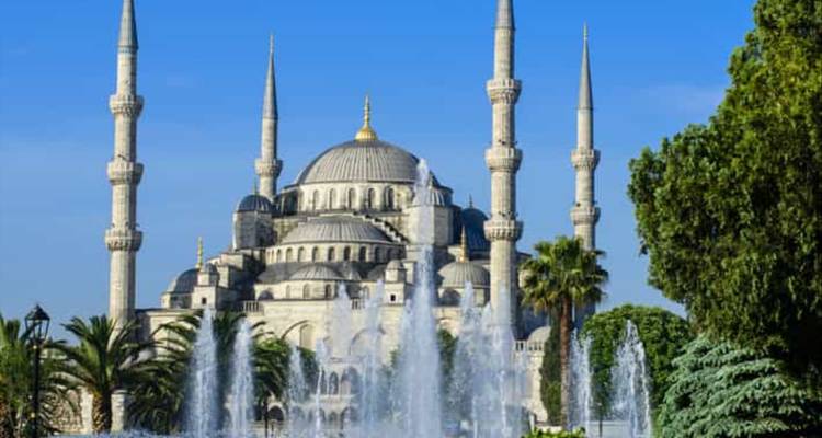 Große Moschee mit Springbrunnen und Bäumen.