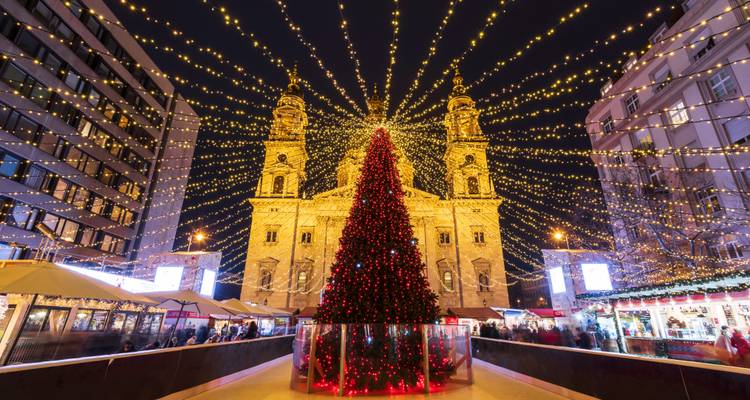 Kerstversieringen en een grote boom op een Europees stadsplein 's nachts.