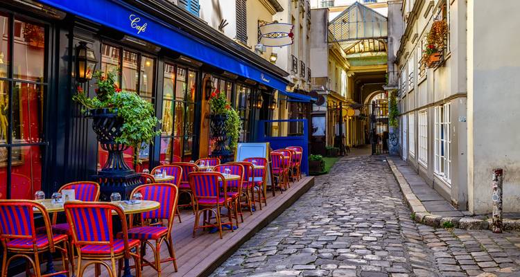 Vista acogedora de una calle con un café y callejón empedrado con arquitectura encantadora.