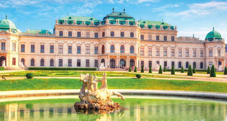 Ein großartiger historischer Palast mit einem Brunnen und einer Statue davor.