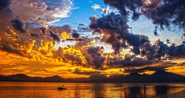 Stunning sunset over a calm sea with dramatic cloud formations.