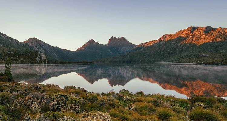 Reflectie van bergen in een kalm meer tijdens de schemering.