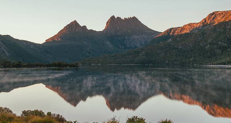 El Cradle Mountain reflejado perfectamente en las aguas tranquilas del lago Dove al amanecer.
