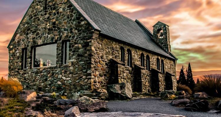 Stenen Kerk van de Goede Herder aan het Tekapomeer onder een dramatische zonsonderganghemel.