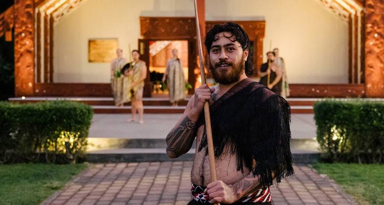 Personas con vestimenta tradicional frente a un edificio cultural.