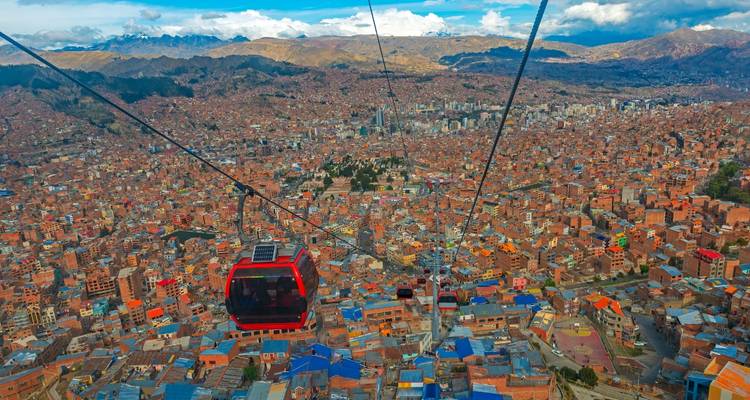 Aerial view of a city with cable cars against a mountainous backdrop.