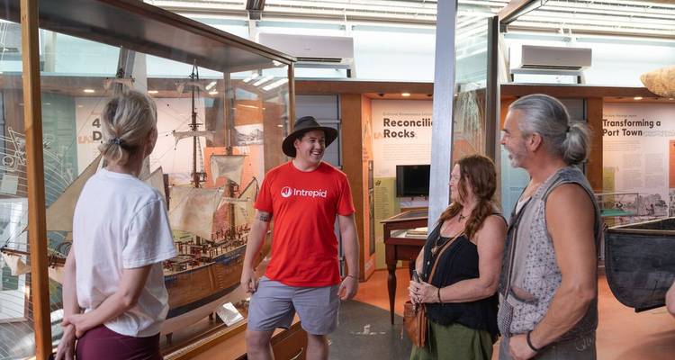 Grupo de personas conversando en un museo con modelos de barcos.