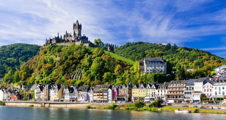 Colorful town with a castle on a hill by the river.