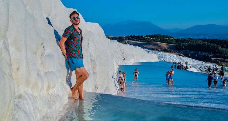 Tourists enjoying the thermal pools with scenic views in the background.