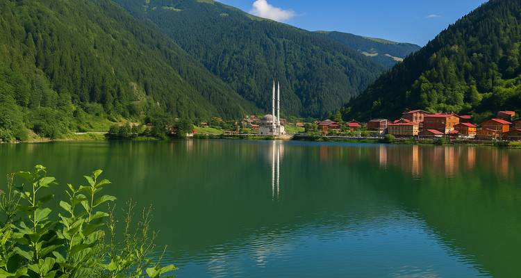 A serene lake scene with a mosque and village nestled between green hills.