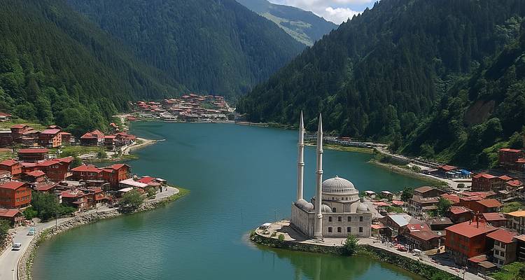 An aerial view of a mosque and a village by a lake between mountains.