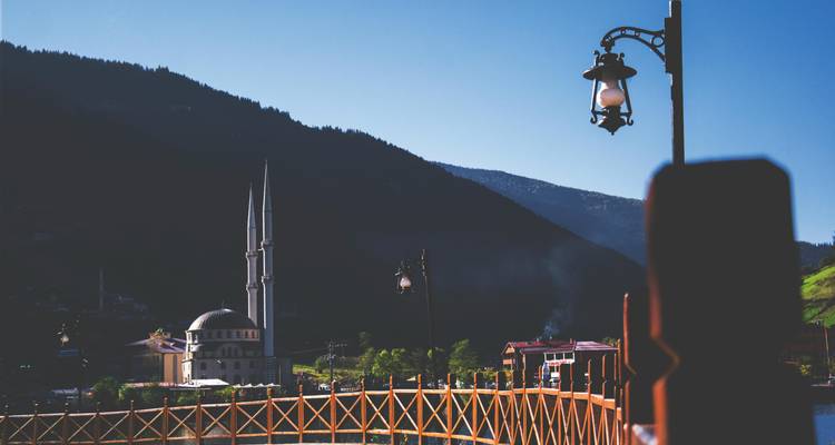 A bridge overlooking a mosque and village during the late afternoon.