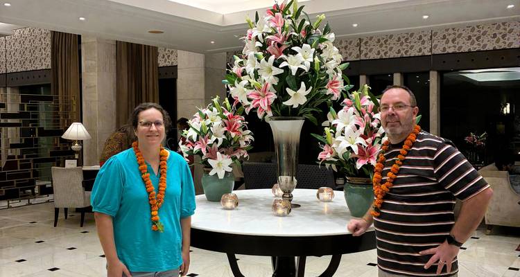 Deux personnes avec des guirlandes de fleurs debout dans le hall d'un hôtel.