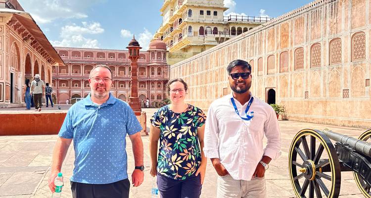 Un groupe de trois personnes posant dans un fort historique avec des façades sculptées.