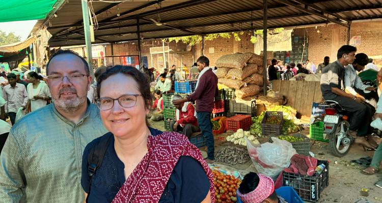 Deux personnes dans un marché animé avec des étals colorés.