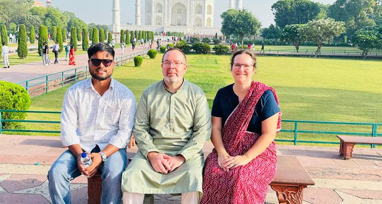 Trois personnes assises avec le Taj Mahal en arrière-plan.