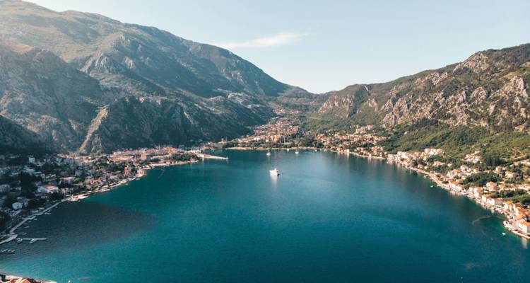 Luftaufnahme einer Küstenstadt, eingebettet zwischen Bergen und einer Bucht.