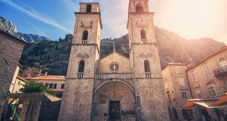 Historische Kirchenfassade mit zwei Glockentürmen in einer Altstadtkulisse.