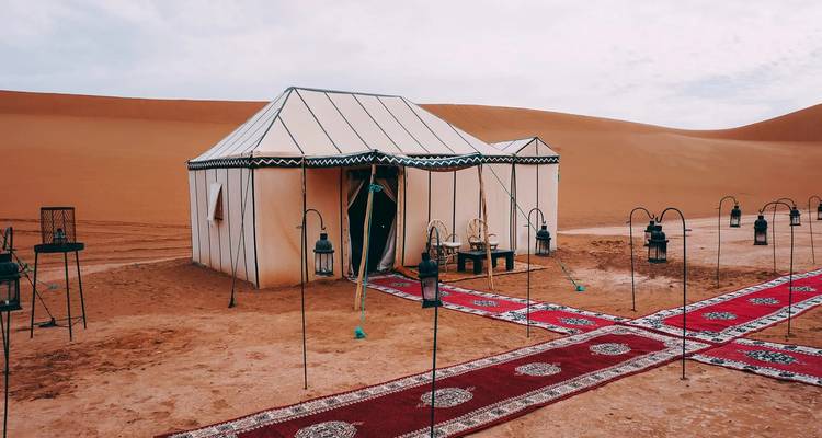 Desert tent setup with traditional decorations in a sand-filled landscape.