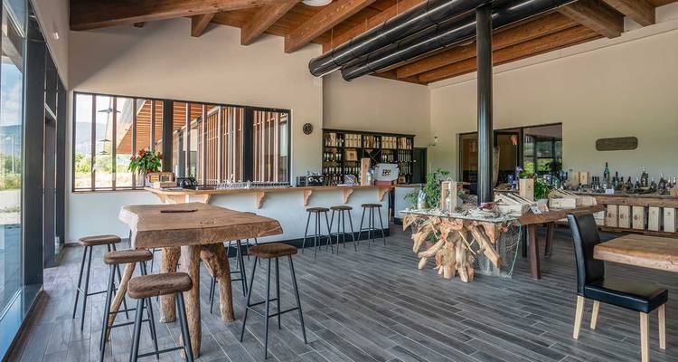 Ein stilvolles Verkostungszimmer mit Holztischen, sichtbaren Balkendecken und Ausstellungen von regionalen Weinen und Produkten.