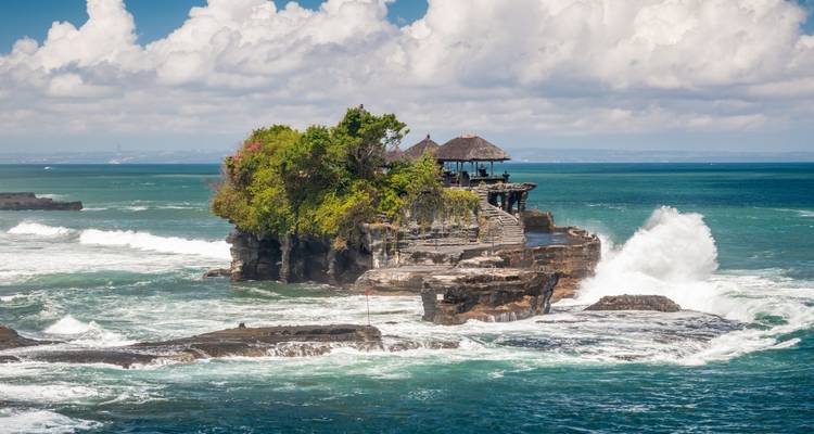 Tanah Lot temple on rocks with waves crashing around.