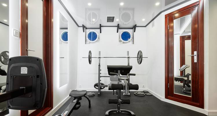Weightlifting equipment in a gym room with view of the sea.