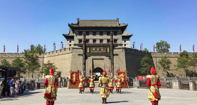 Los guardias disfrazados realizan una exhibición ceremonial frente a la imponente puerta de la muralla de la ciudad antigua bajo un cielo azul despejado.