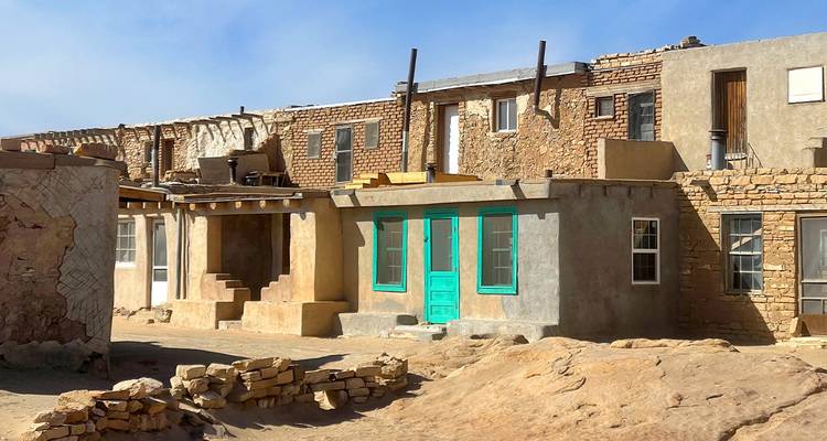 Traditionelle Lehmziegelbau- und Steinwohnungen mit türkisfarbenen Türen in einem historischen Pueblo des Südwestens.
