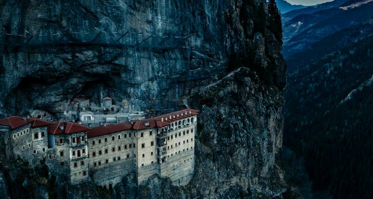 Monastery at dusk set against a mountainous landscape.