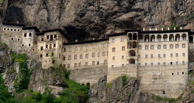 Historic monastery facade set against a rock face.