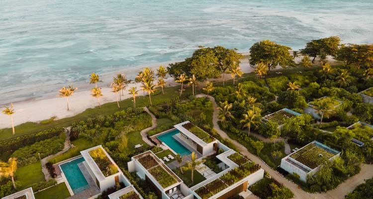 Vue aérienne d'un complexe hôtelier au bord de la plage avec une végétation luxuriante.