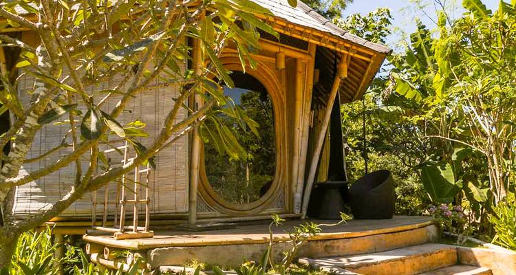 Patio extérieur d'une hutte tropicale entourée de verdure.