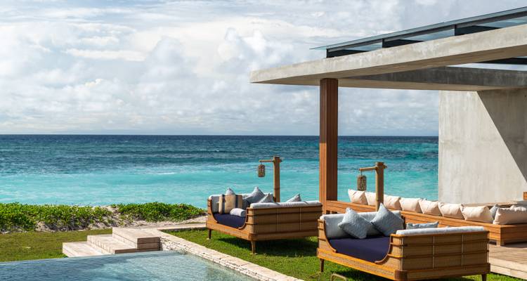 Villa moderne en bord de mer avec vue sur l'océan et sièges au bord de la piscine.