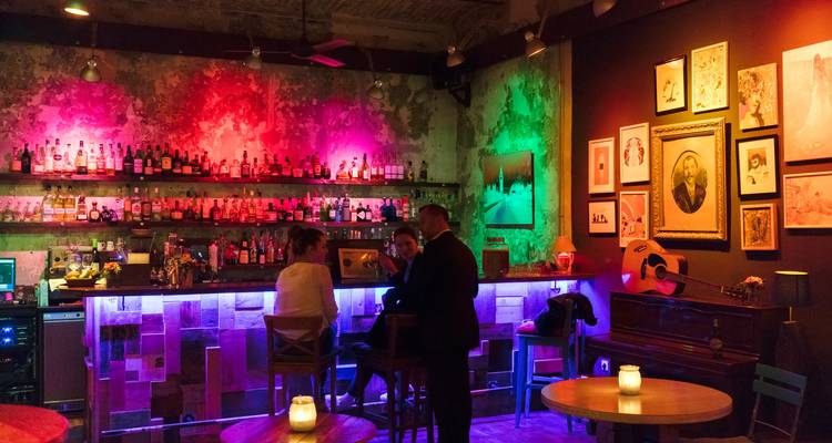 Schwach beleuchtete Bar mit bunten Lichtern und Gästen.