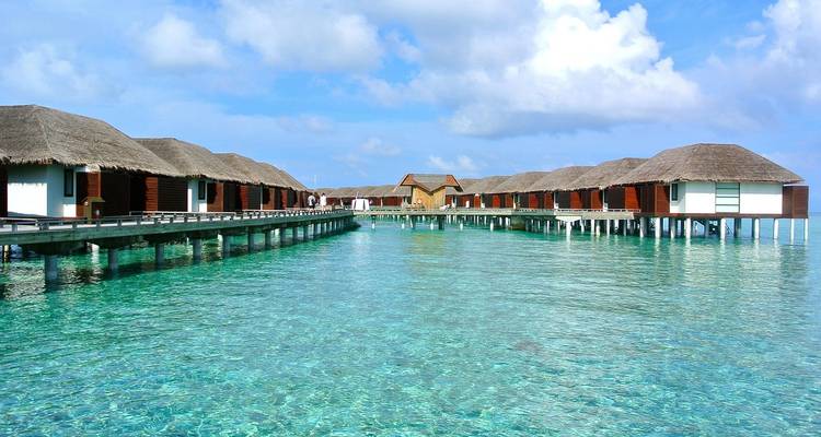 Overwater villas in a tropical Maldives resort with clear turquoise water.