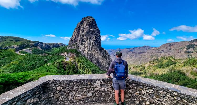 Un viajero con una mochila azul admira el imponente monolito Roque Agando rodeado de vistas amplias de la isla.