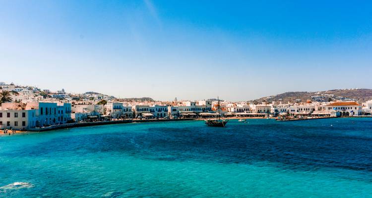 Port area with blue sea and traditional buildings in Mykonos, Greece.