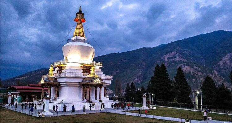Chorten in der Abenddämmerung im Himalaya mit einigen Menschen drumherum.