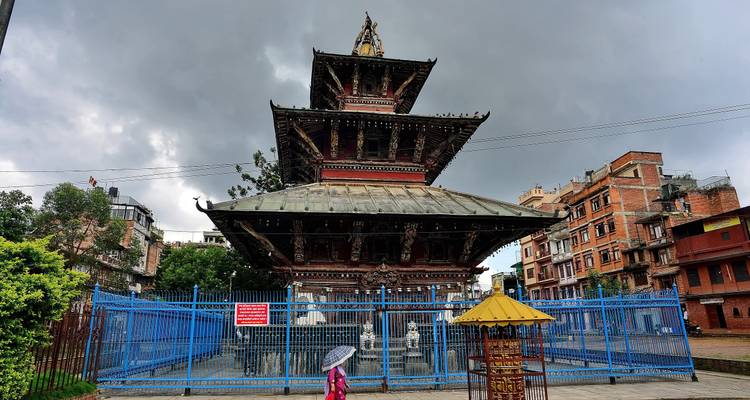 Mehrstöckiger Pagodentempel umgeben von blauem Sicherheitszaun unter bedrohlich grauen Himmeln.