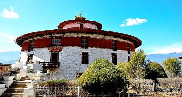 Rundes Wachturm-Museum Ta Dzong aus weißem Stein vor einem strahlend blauen Himmel in Paro.