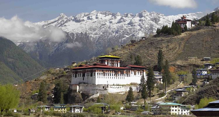 Paro Dzong Festungskloster auf einem Hügel mit schneebedeckten Himalayas im Hintergrund.