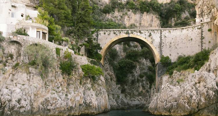 Un pont historique en pierre au-dessus d'un cours d'eau étroit.