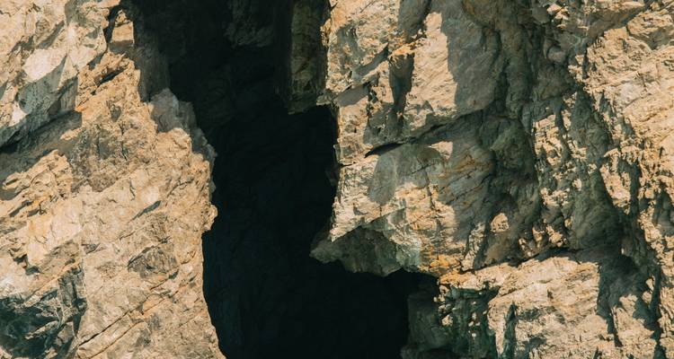 Entrée de grotte dans un paysage rocheux accidenté.